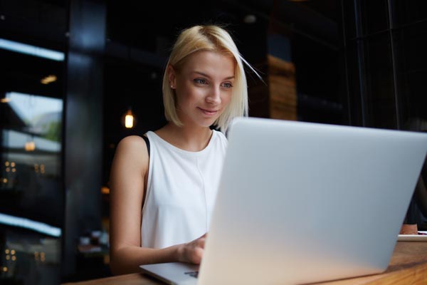 A young woman works in a coffee shop on her laptop